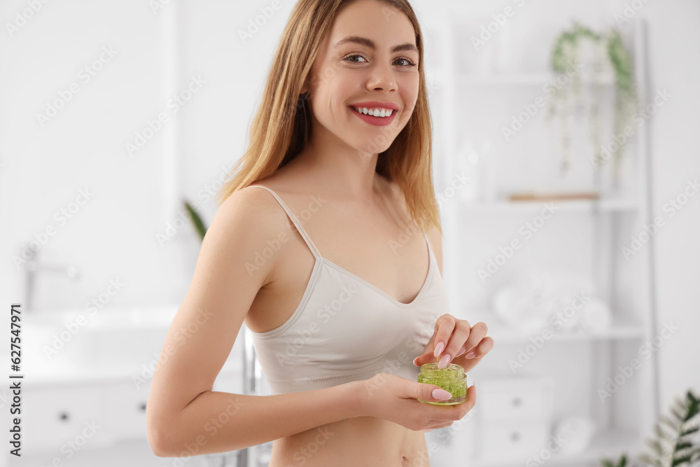 Young woman with anti-cellulite scrub in bathroom