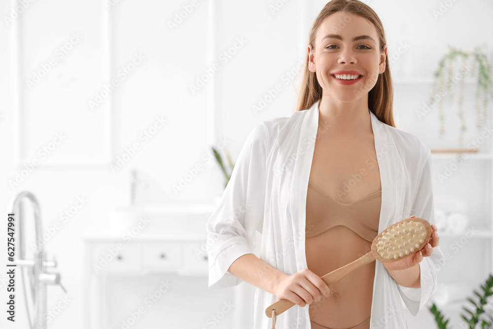 Young woman with anti-cellulite brush in bathroom