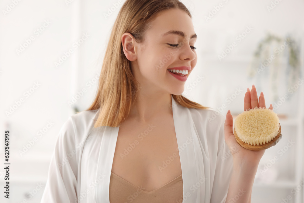 Young woman with anti-cellulite brush in bathroom, closeup