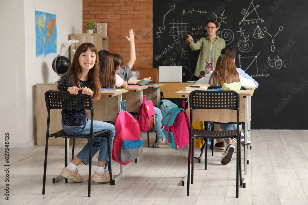 Little pupils with backpacks having lesson in classroom