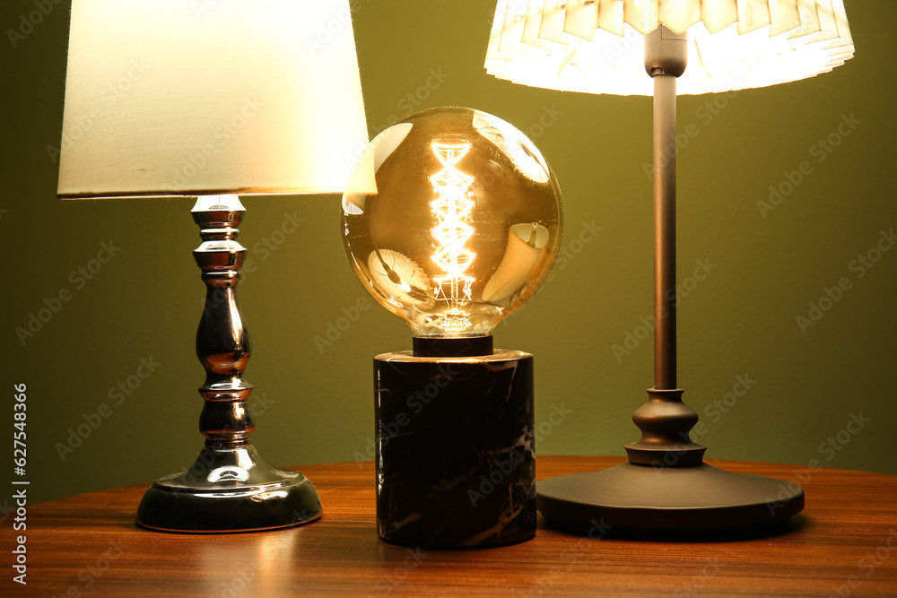 Different glowing lamps on wooden table in dark room