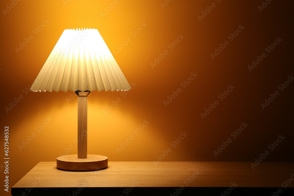 Glowing lamp on wooden table in dark room