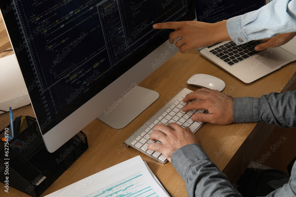 Male programmers working at table in office, closeup