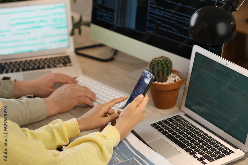 Programmers working at table in office, closeup