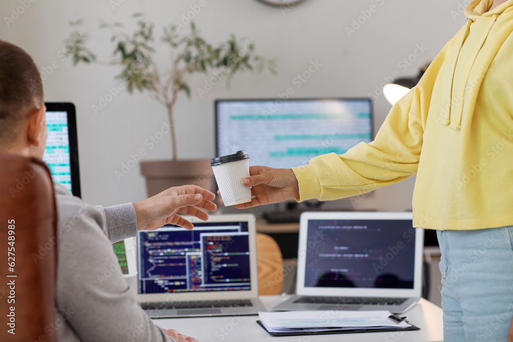 Programmers with cup of coffee in office, closeup