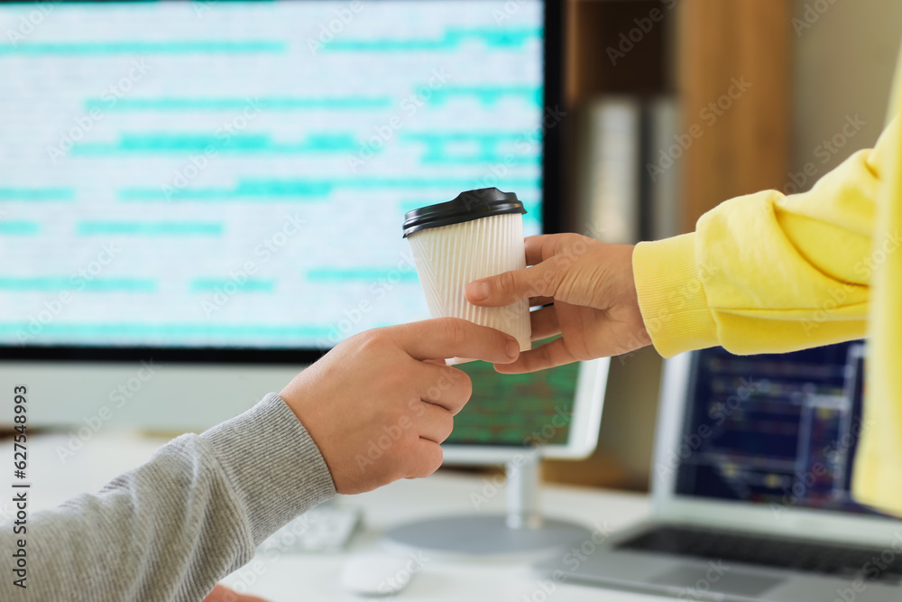 Programmers with cup of coffee in office, closeup