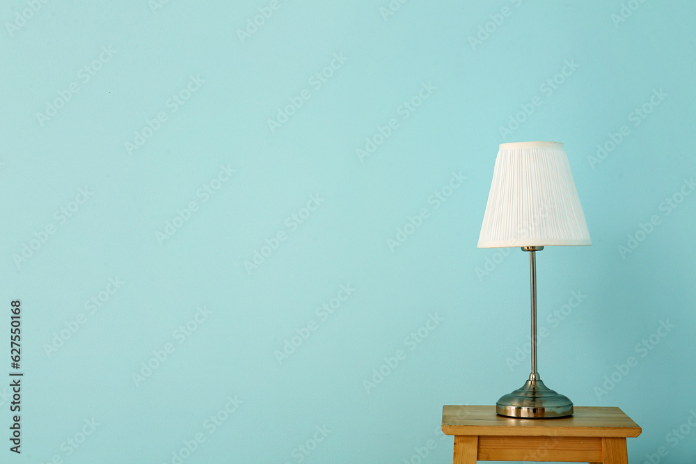 Lamp on wooden table near blue wall