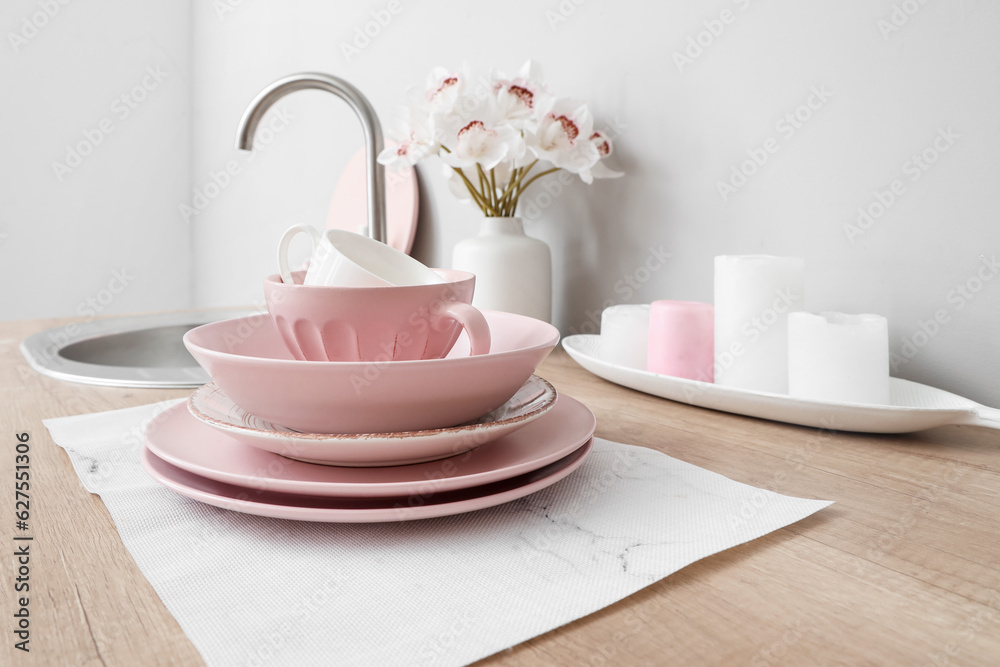 Clean dishes and vase with orchid flowers on kitchen counter, closeup