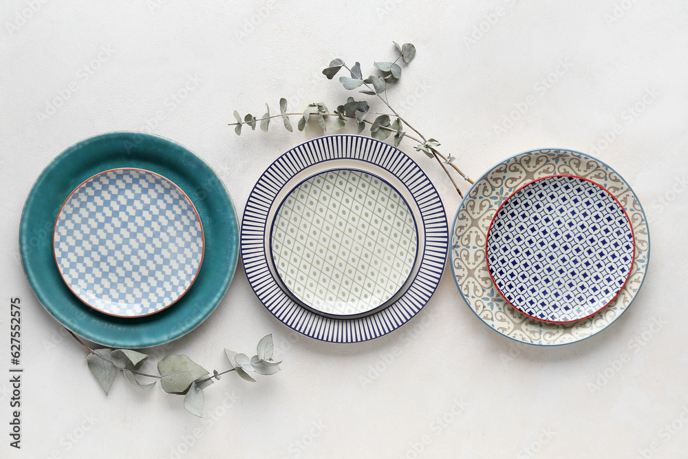 Different clean plates and eucalyptus branches on grey table