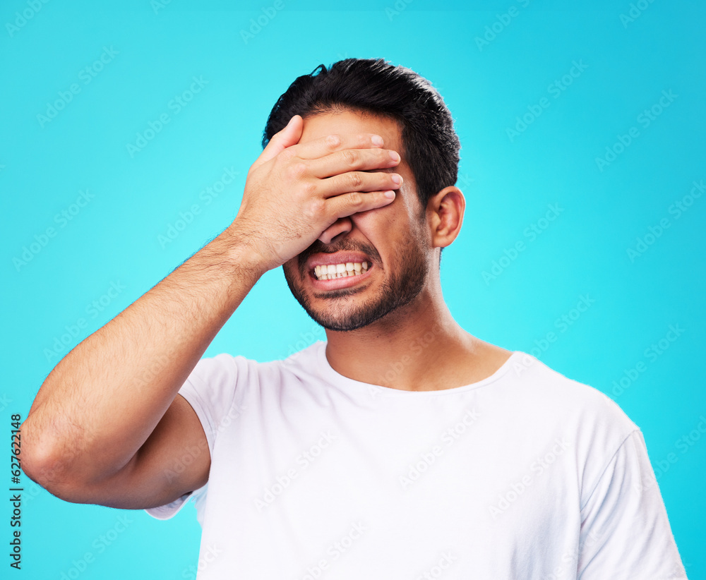 Scared, covering eyes and a man on a blue background for fear, anxiety or angry with a problem. Ment