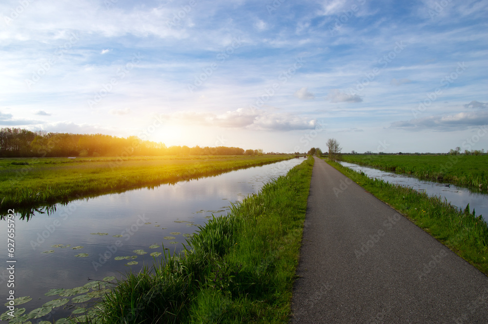 Landscape green meadow and canal with clear water