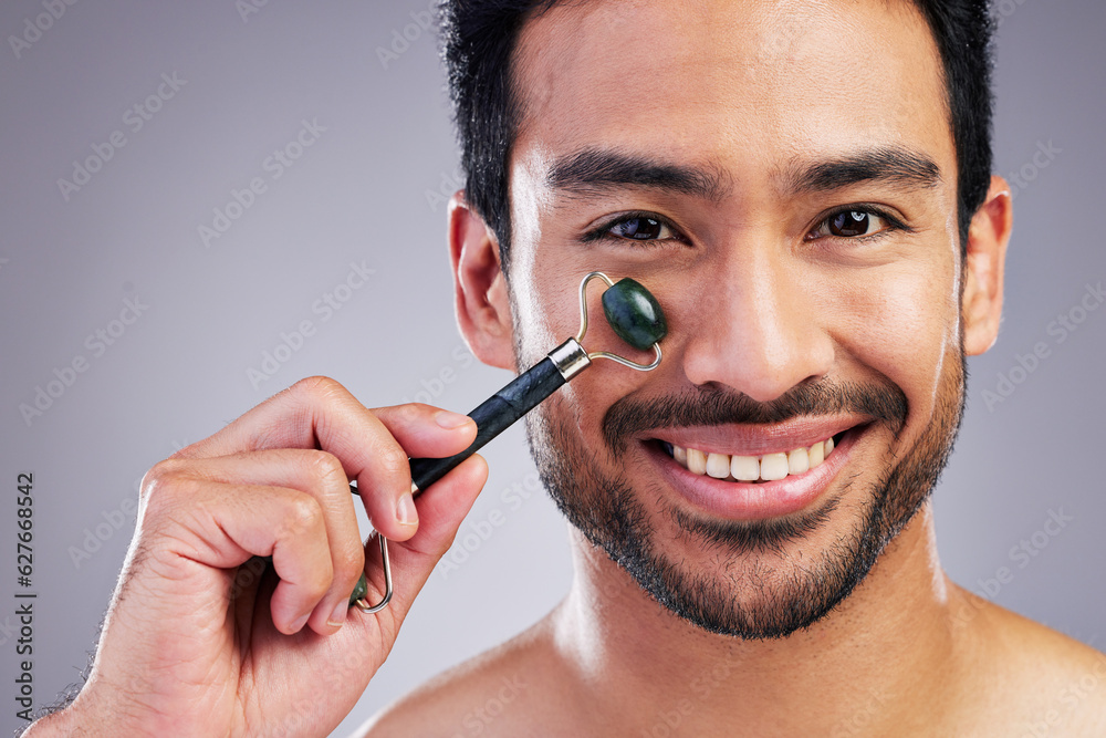 Happy man, portrait or face massage with roller or product for healthy skincare on studio background