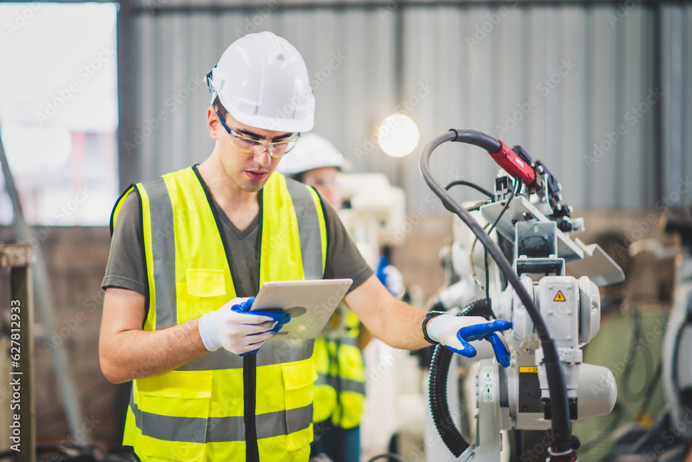 Engineers team mechanic using computer controller Robotic arm for welding steel in steel factory wor