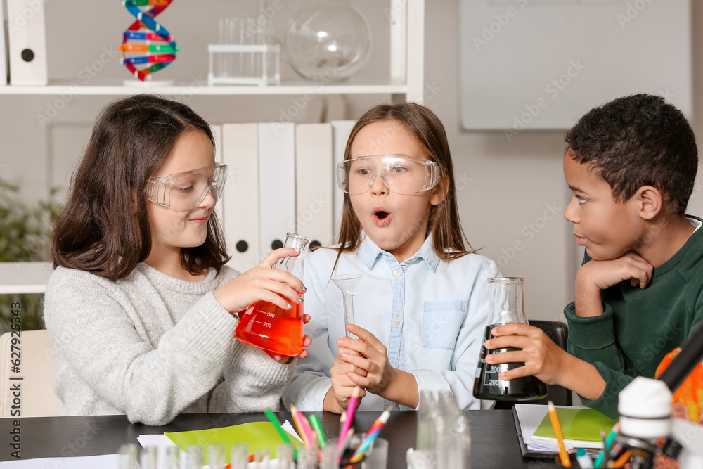 Little children conducting chemistry experiment in science classroom