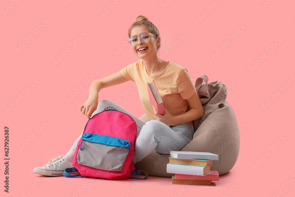 Female student with books and backpack on pink background