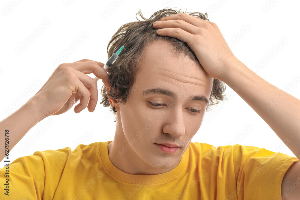 Young man with injection for hair growth on white background, closeup