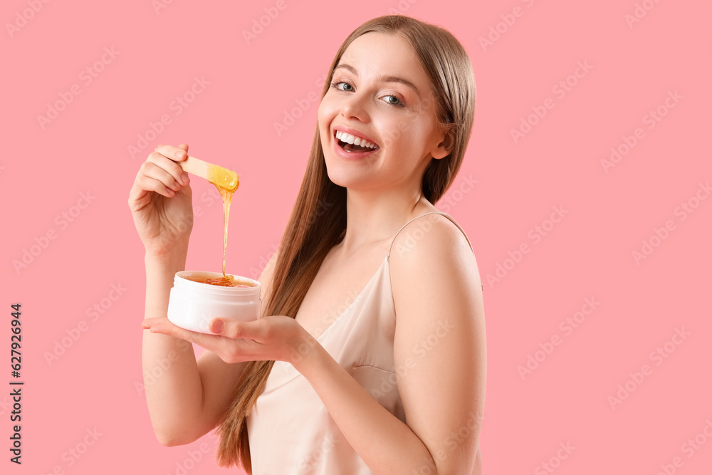 Pretty young woman with sugaring paste on pink background