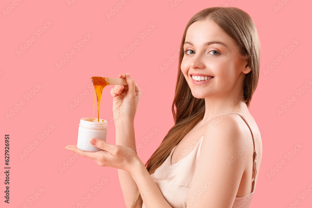 Pretty young woman with sugaring paste on pink background