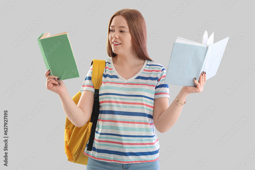 Female student with books on light background