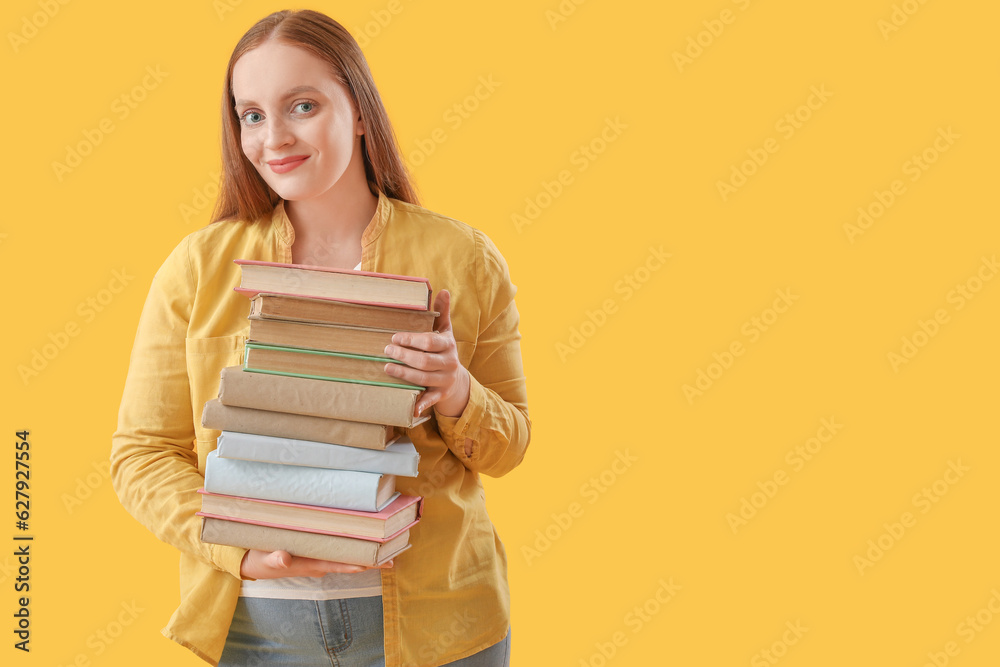 Young woman with stack of books on yellow background