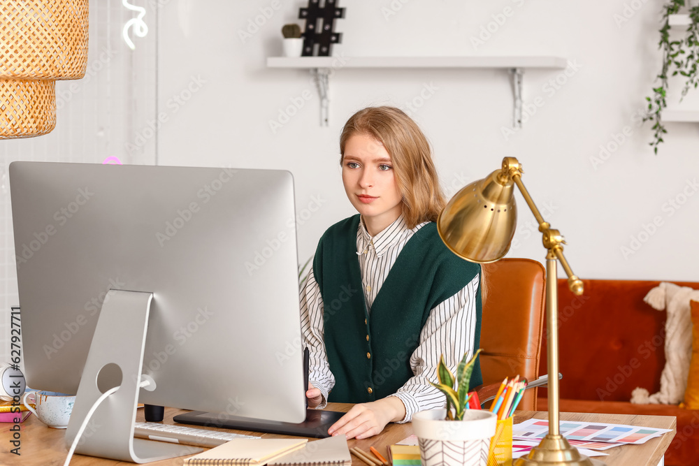 Female graphic designer working with tablet at table in office