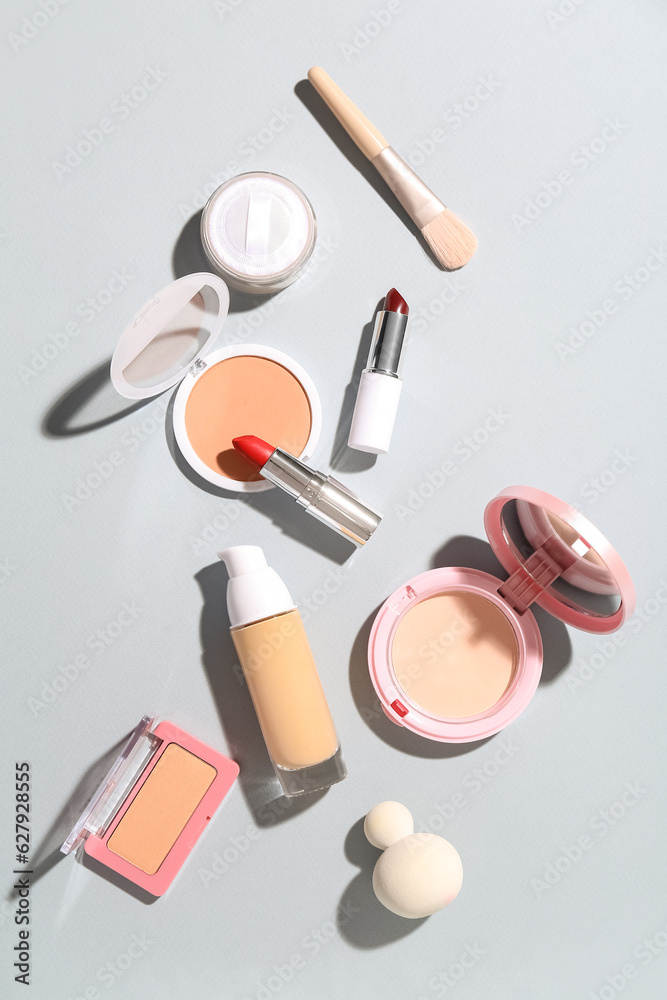 Decorative cosmetics with makeup brush and sponges on grey background