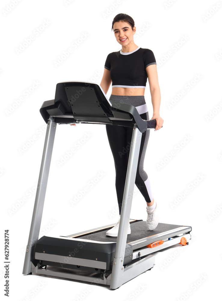 Sporty young woman training on treadmill against white background