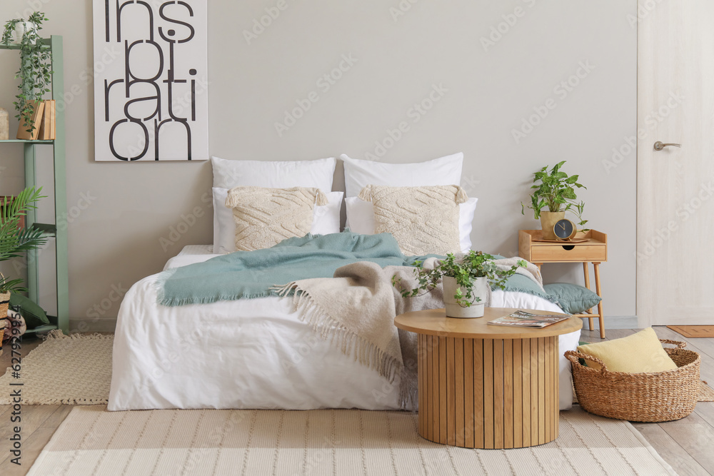 Interior of bedroom with cozy bed and houseplant on coffee table