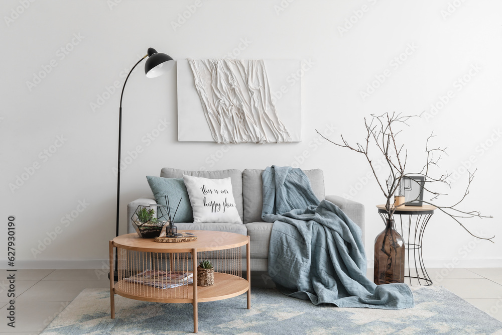 Interior of cozy living room with grey sofa and coffee table near white wall