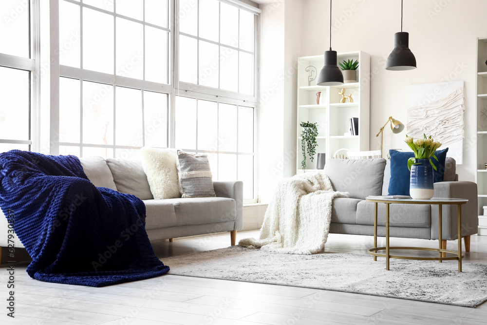 Interior of bright living room with cozy sofas and coffee table near big window