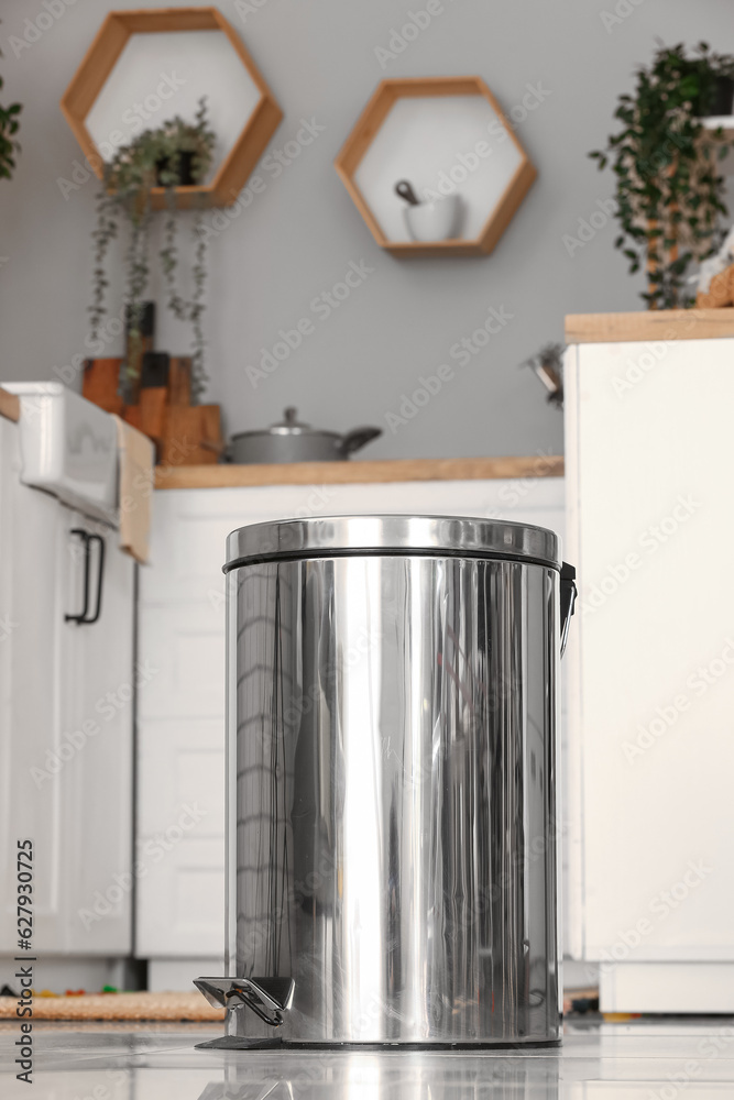 Metallic trash bin on floor in modern kitchen