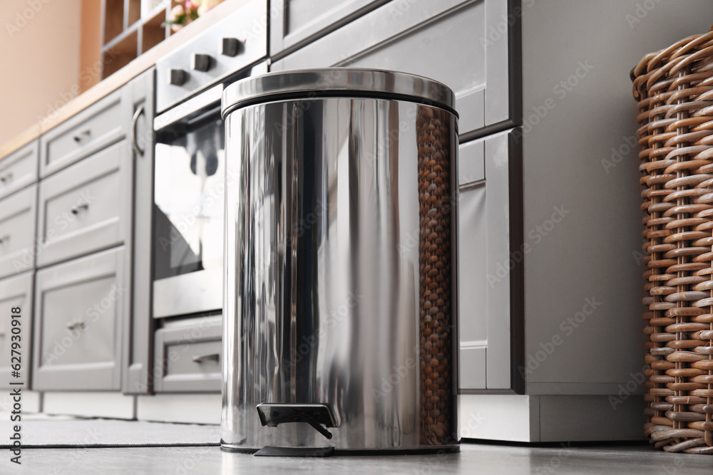 Metallic trash bin on floor in modern kitchen