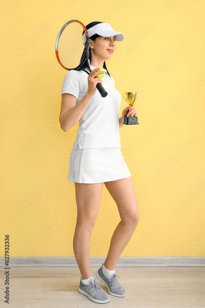 Female tennis player with gold cup near yellow wall