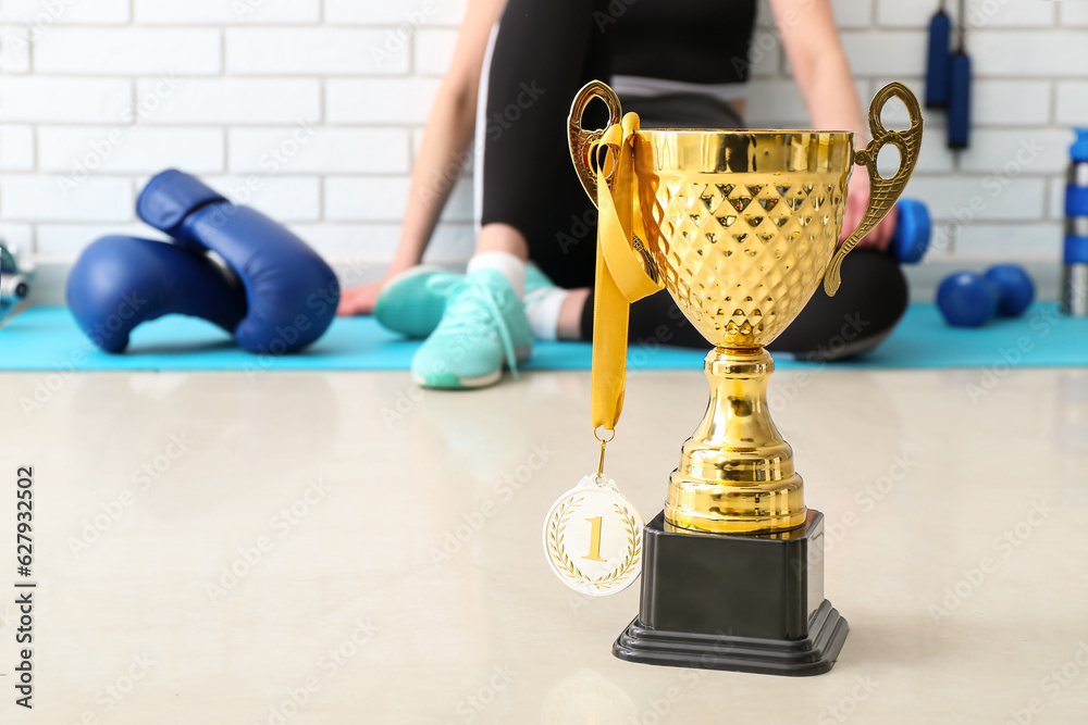 Gold cup with first place medal on floor in gym, closeup