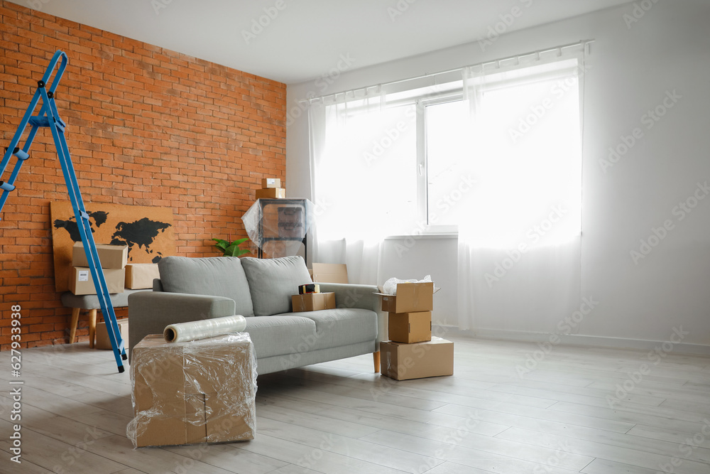 Sofa with cardboard boxes in living room on moving day