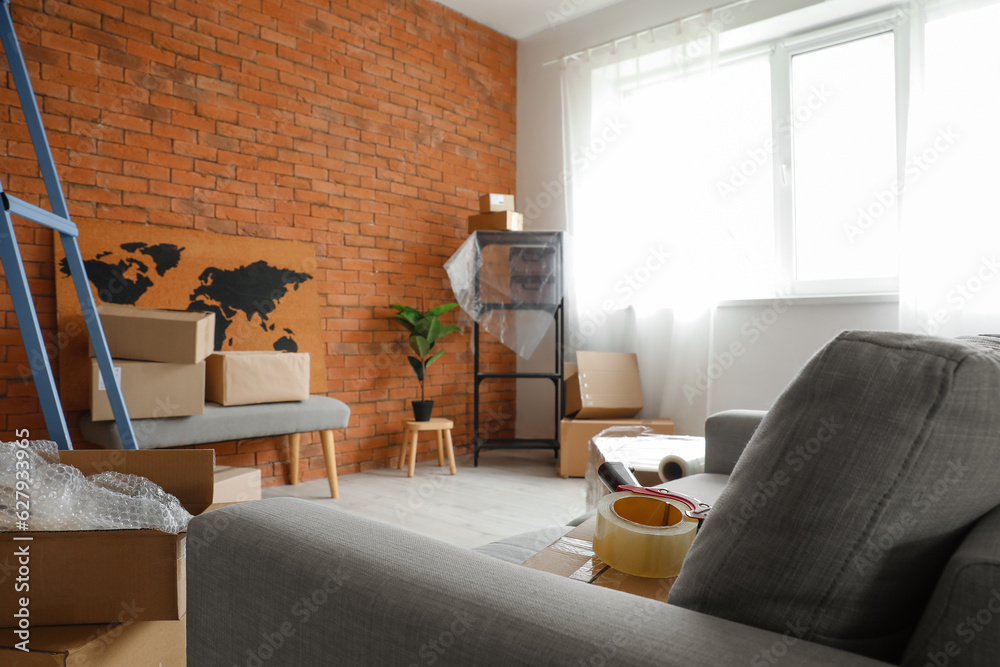 Sofa with adhesive tape and cardboard boxes in living room on moving day, closeup