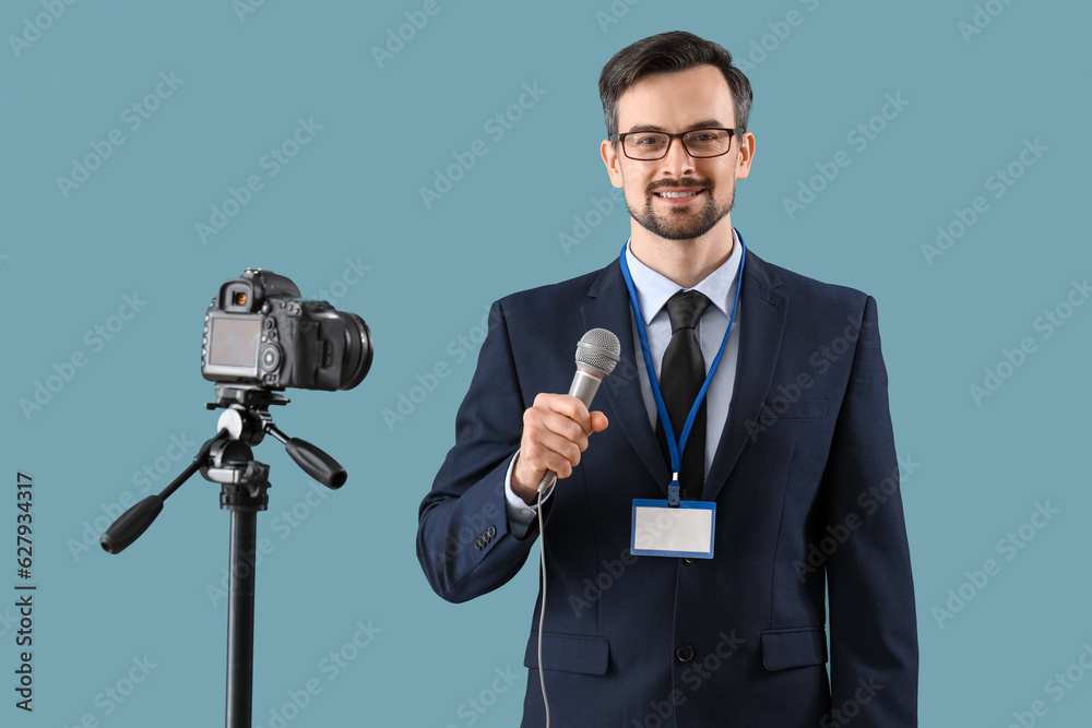 Male journalist with microphone recording video on blue background