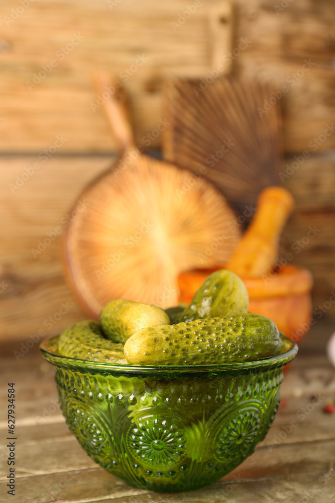 Bowl with tasty canned cucumbers on wooden table