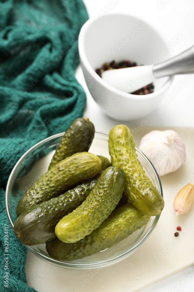 Bowl with tasty fermented cucumbers on light background