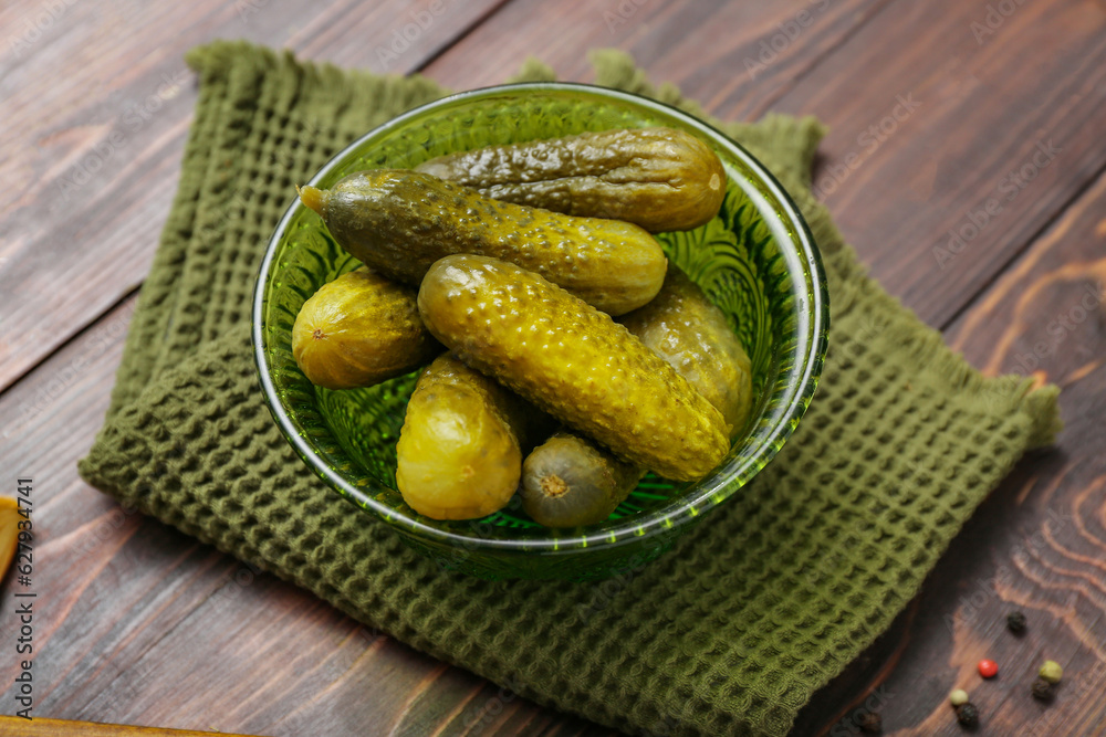 Bowl with tasty fermented cucumbers on wooden background