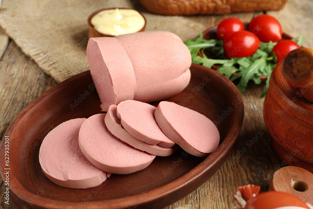 Plate with tasty boiled sausage on wooden background