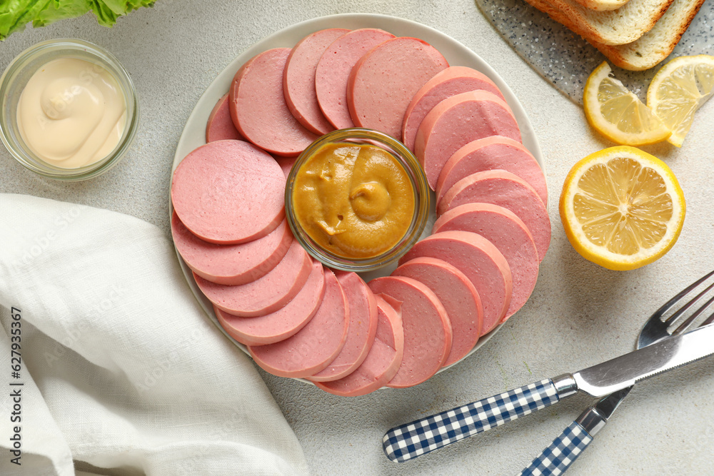 Plate with tasty sliced boiled sausage and sauces on light background