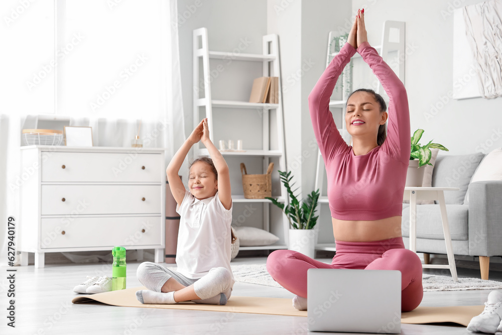 Working mother with her little daughter doing yoga at home