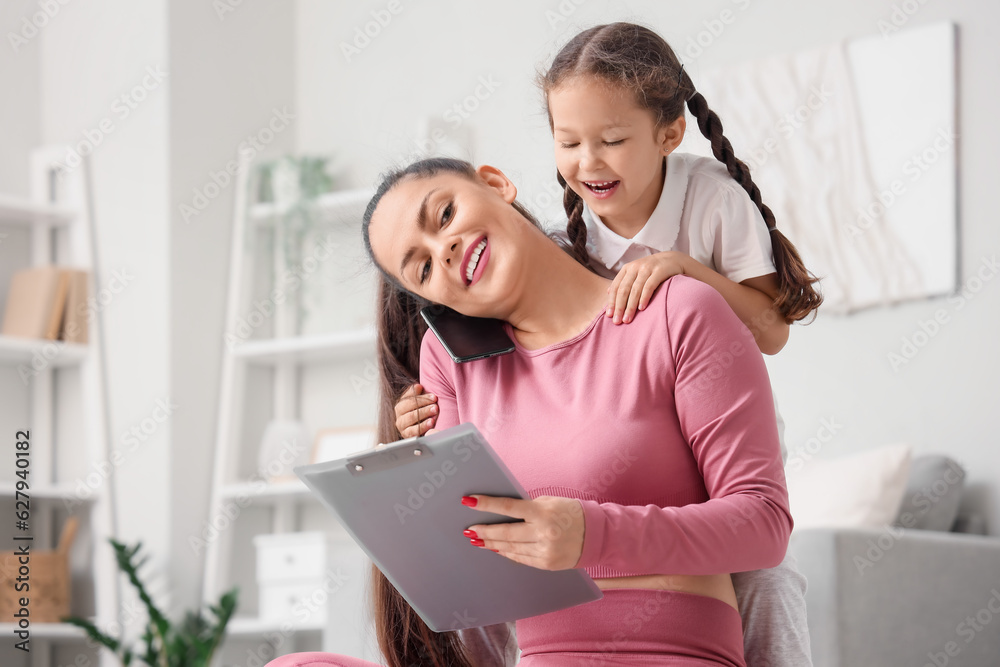 Working mother with her little daughter at home