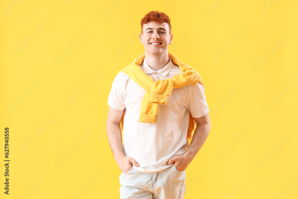 Young redhead man on yellow background