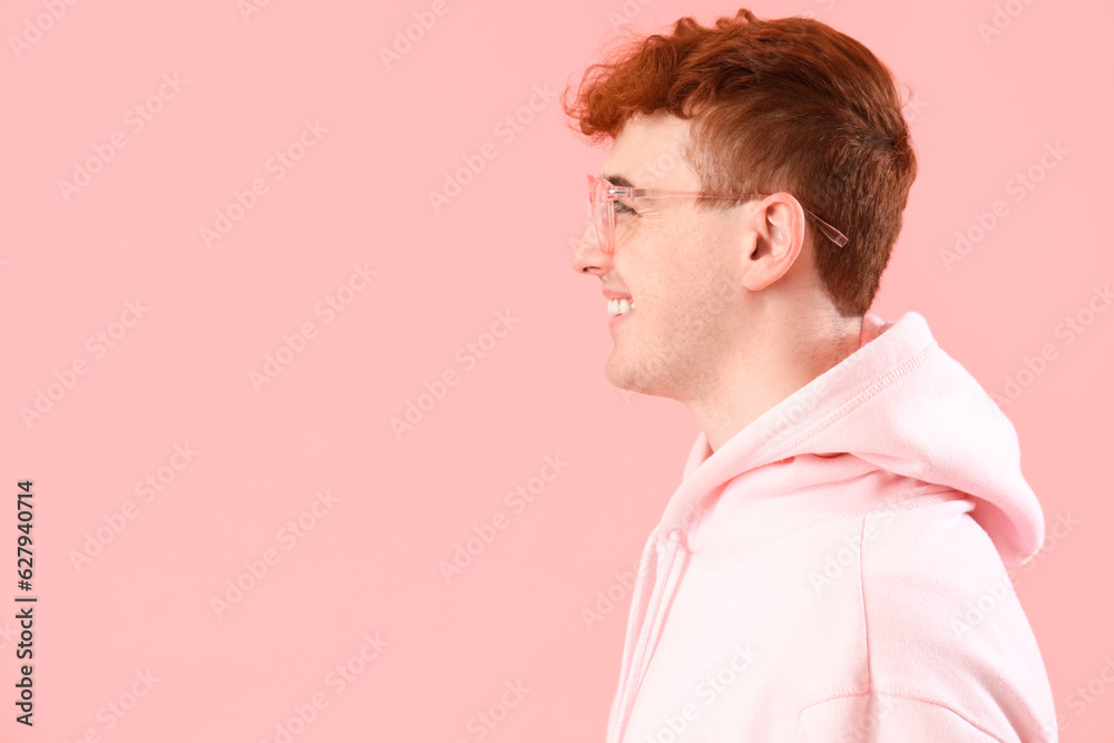 Young redhead man in eyeglasses on pink background, closeup