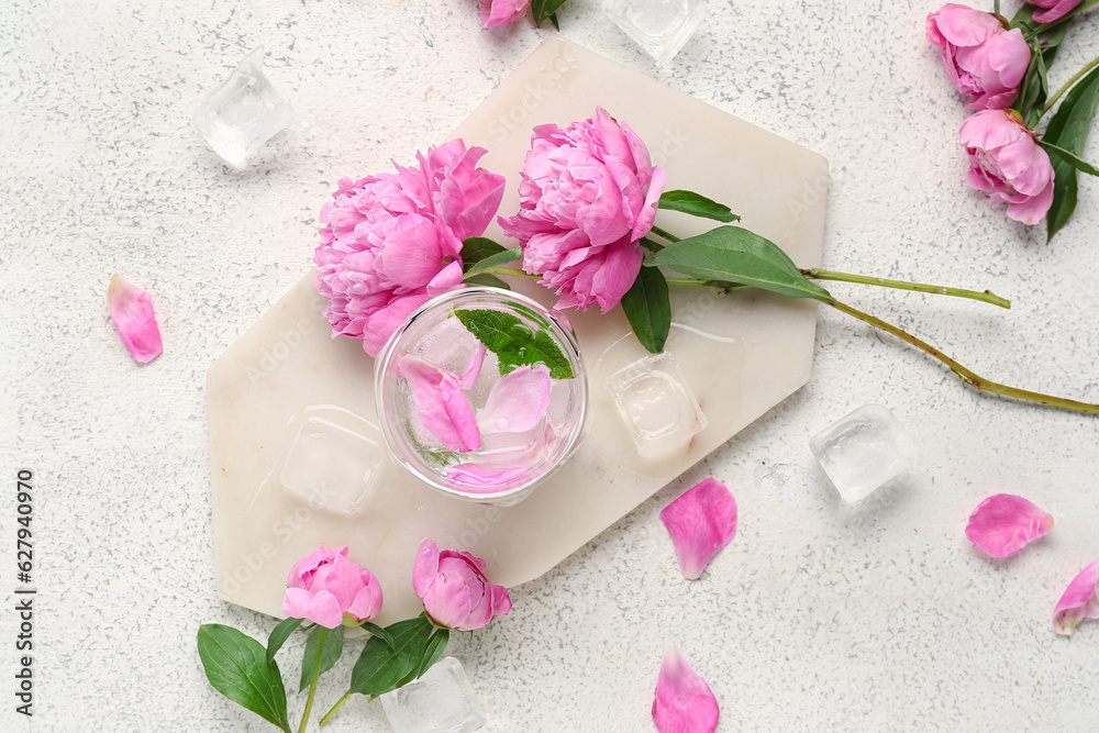 Composition with glass of water, ice cubes and beautiful peony flowers on light background