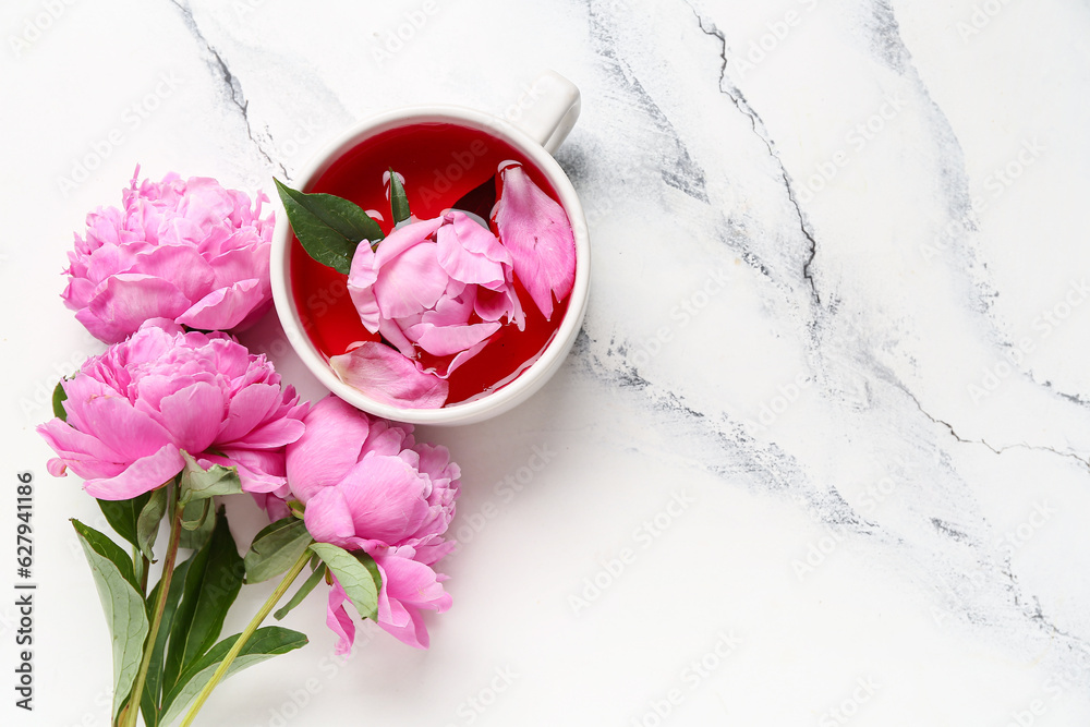 Cup of tea and beautiful peony flowers on light background