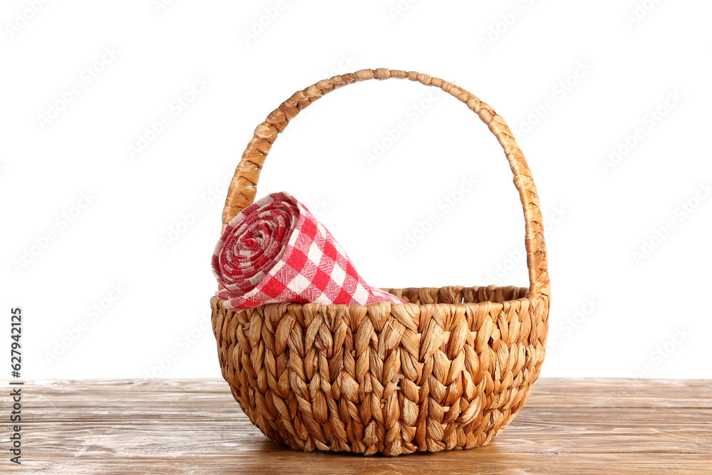 Wicker basket with rolled napkin on wooden table against white background