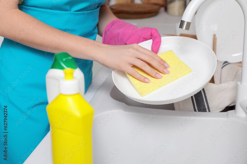 Young woman washing dishes in kitchen, closeup